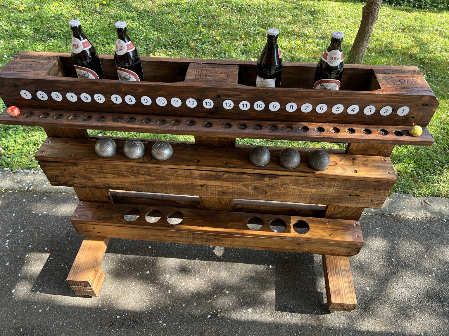Vue de dessus du boulier de pétanque en bois de palette avec les boules et les bouteilles