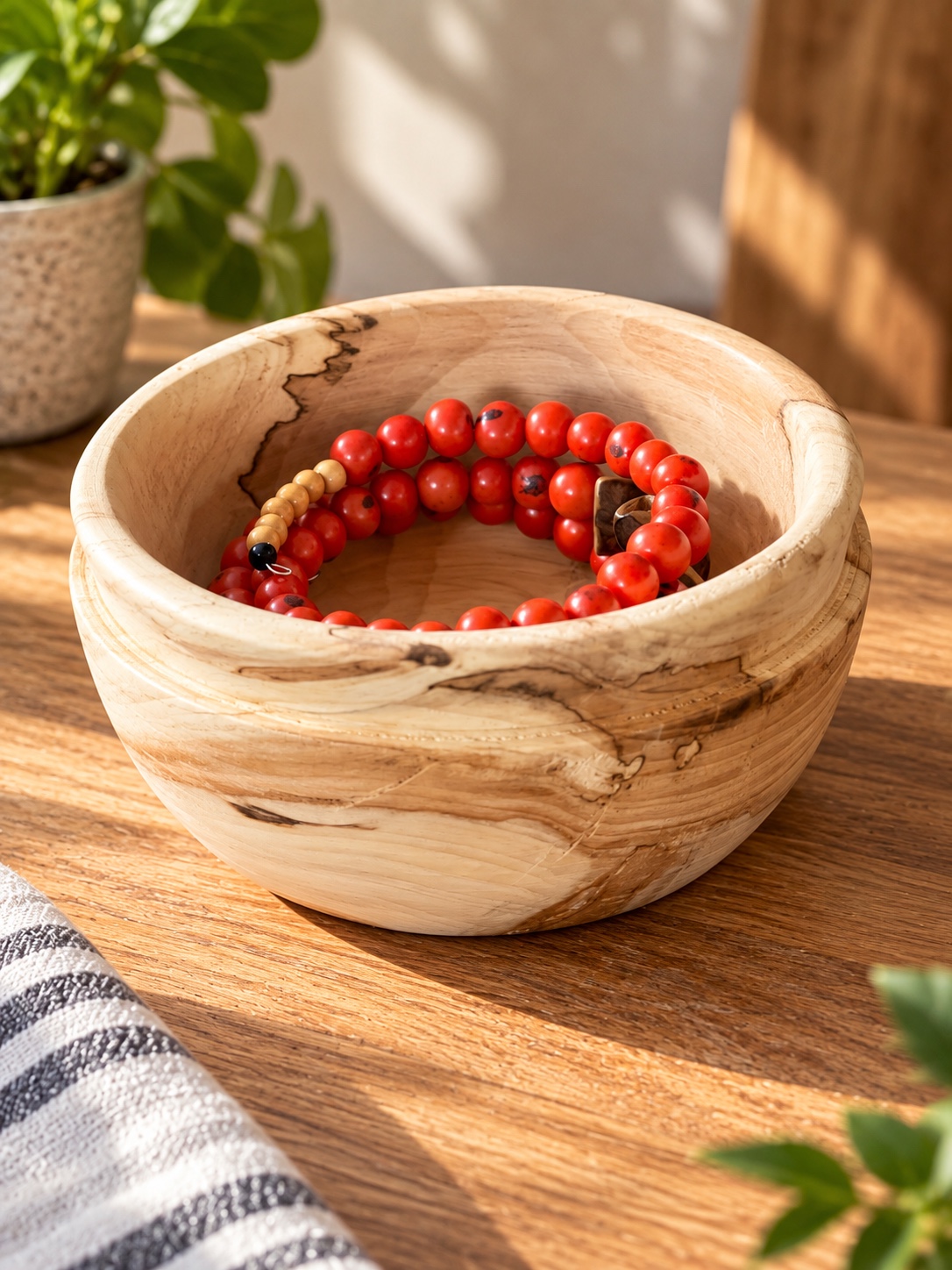 Coupelle en noyer veiné contenant un bracelet rouge