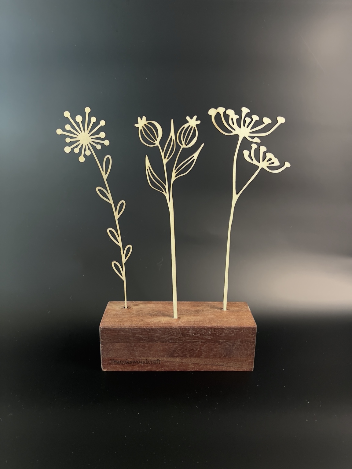 Trois fleurs finement découpées au laser sur un socle en chêne