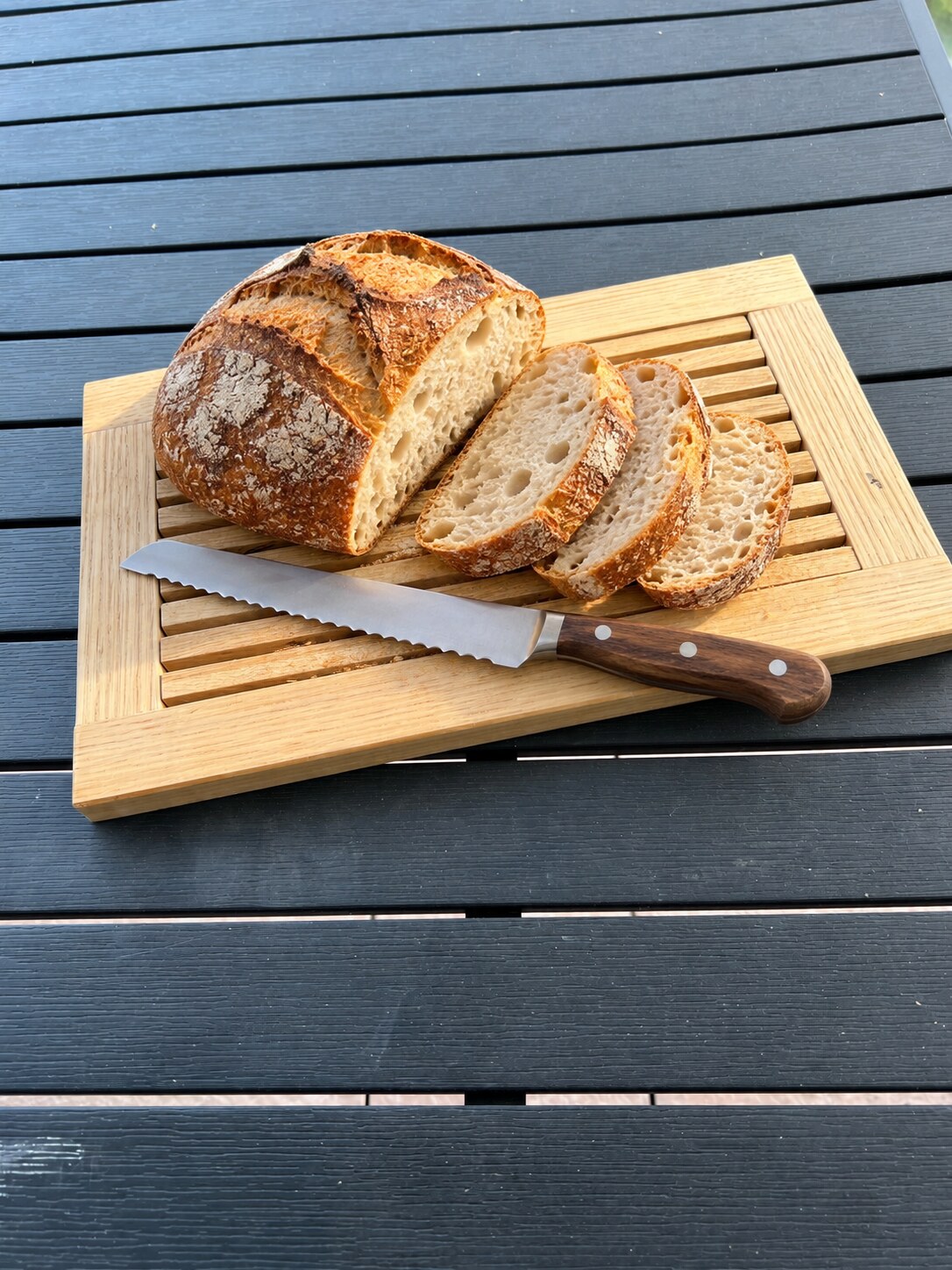 Planche à pain en chêne utilisée avec un pain tranché et un couteau à pain