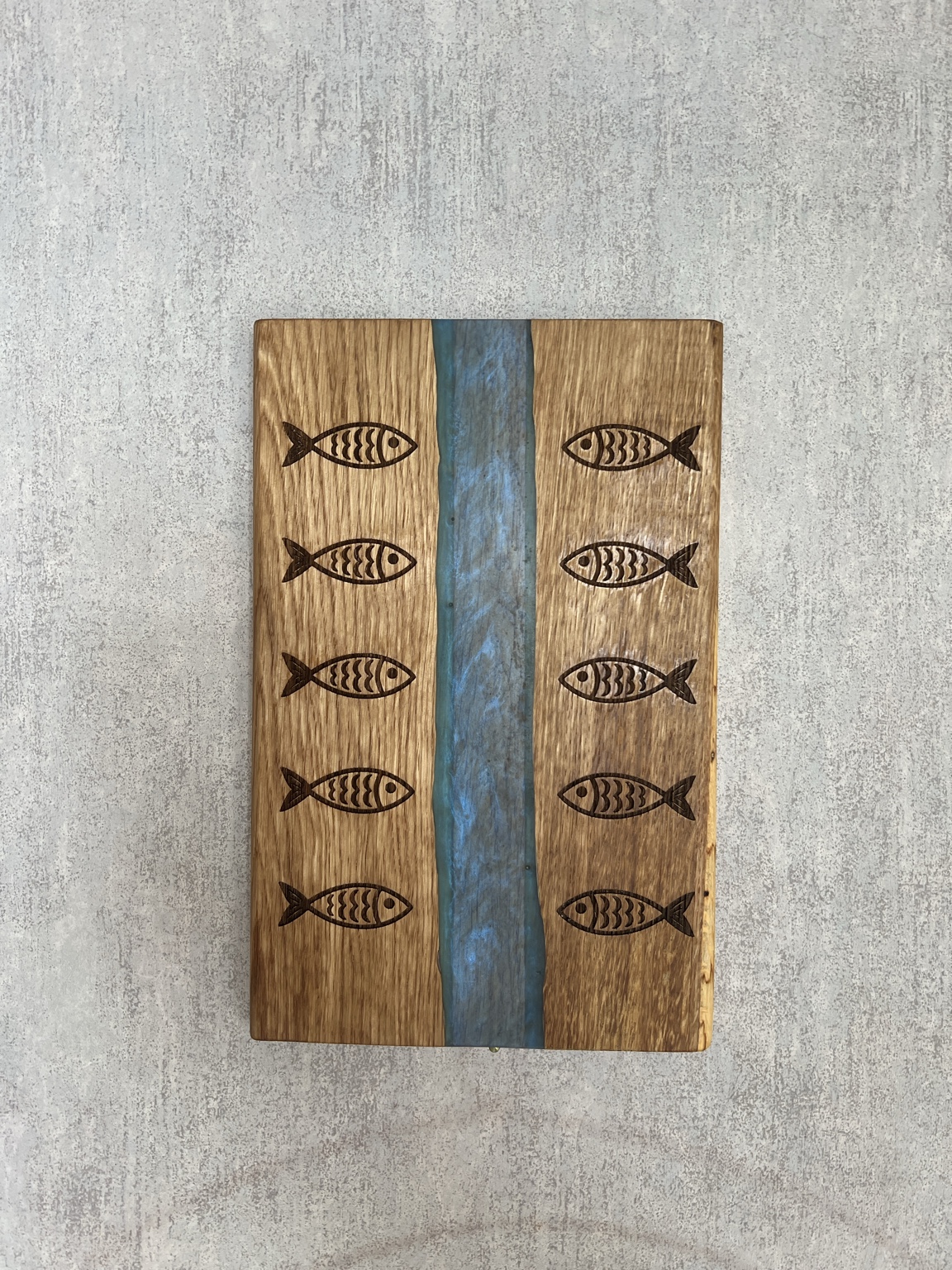 Vue de dessus de la planche gravée de poissons et de sa rivière en résine époxy bleue