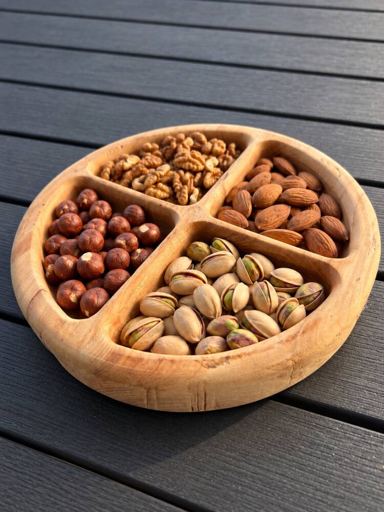 Plateau apéritif rond à quatre compartiments garni de noix, amandes, noisettes et pistaches