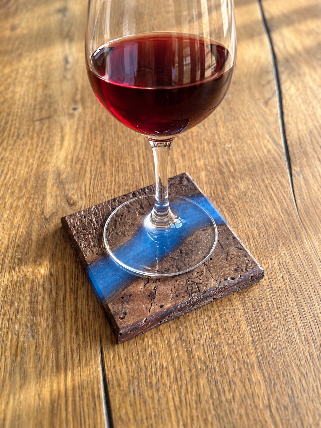 Verre de vin posé sur un sous-verre en noyer vermoulu traversé d’une rivière époxy bleue