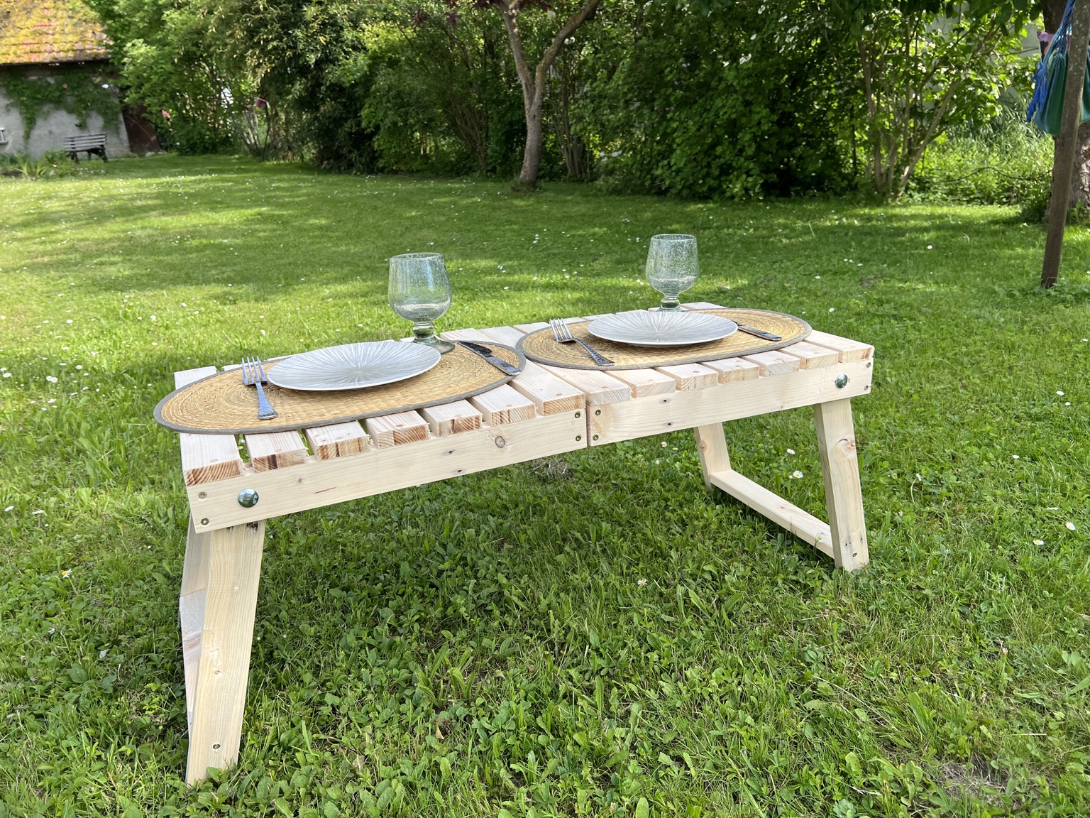 Table de pique-nique pliante en bois de palette installée dans l’herbe